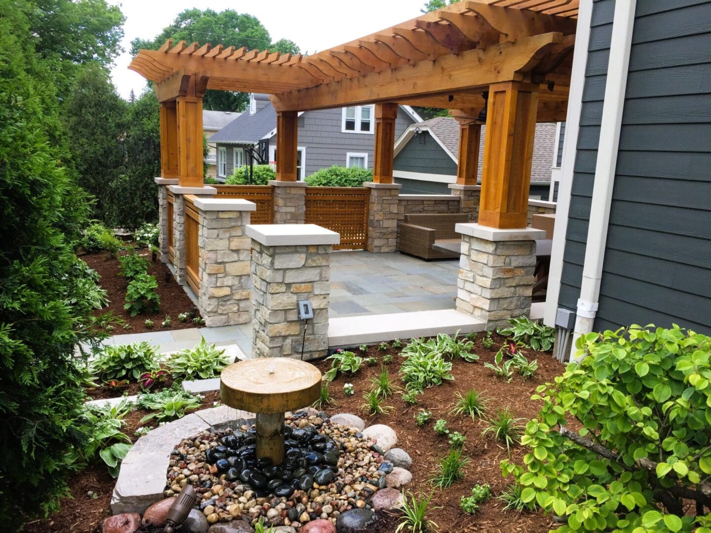 Wooden pergola installed over bluestone patio with custom stone pillars in Downers Grove, IL